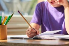 A child using colouring pencils at a desk.