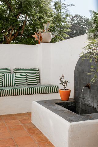 minimaluxe backyard with concrete in built seating and green and white pillows