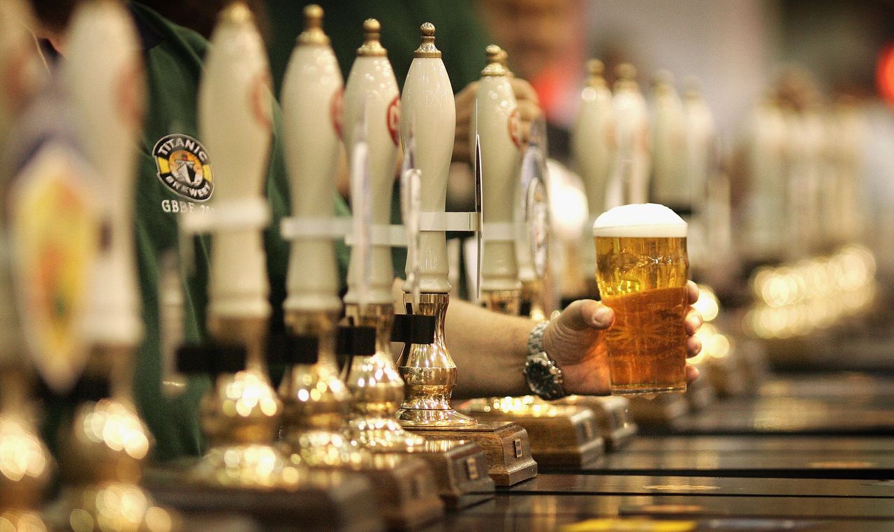 A man holds a glass of beer.