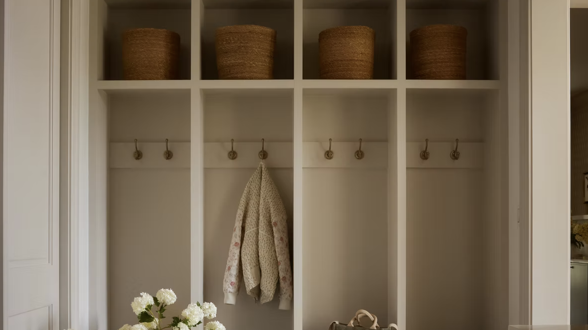 coat hanging in white joinery with baskets on shelves above it