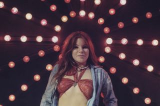 A woman wearing a halter bra top, poses with her head at the centre of disco lights radiating outward, circa 1975.
