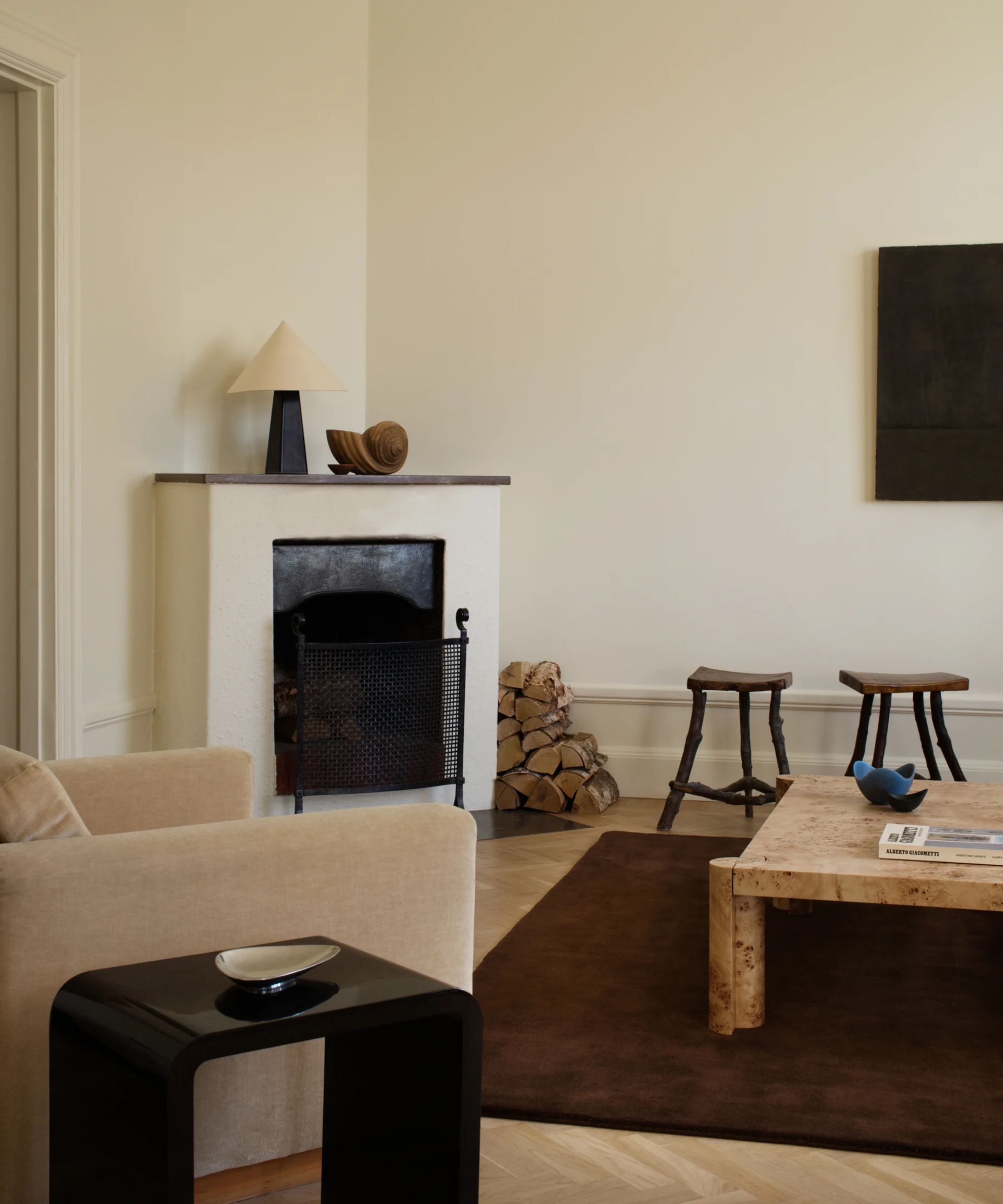 modern meets vintage mid century living room styled with a large plush chocolate brown rug, burl wood coffee table and neutral arm chair