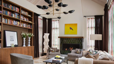 living room with a large black and gold chandelier, a built-in bookshelf wall, a couch, and three chairs