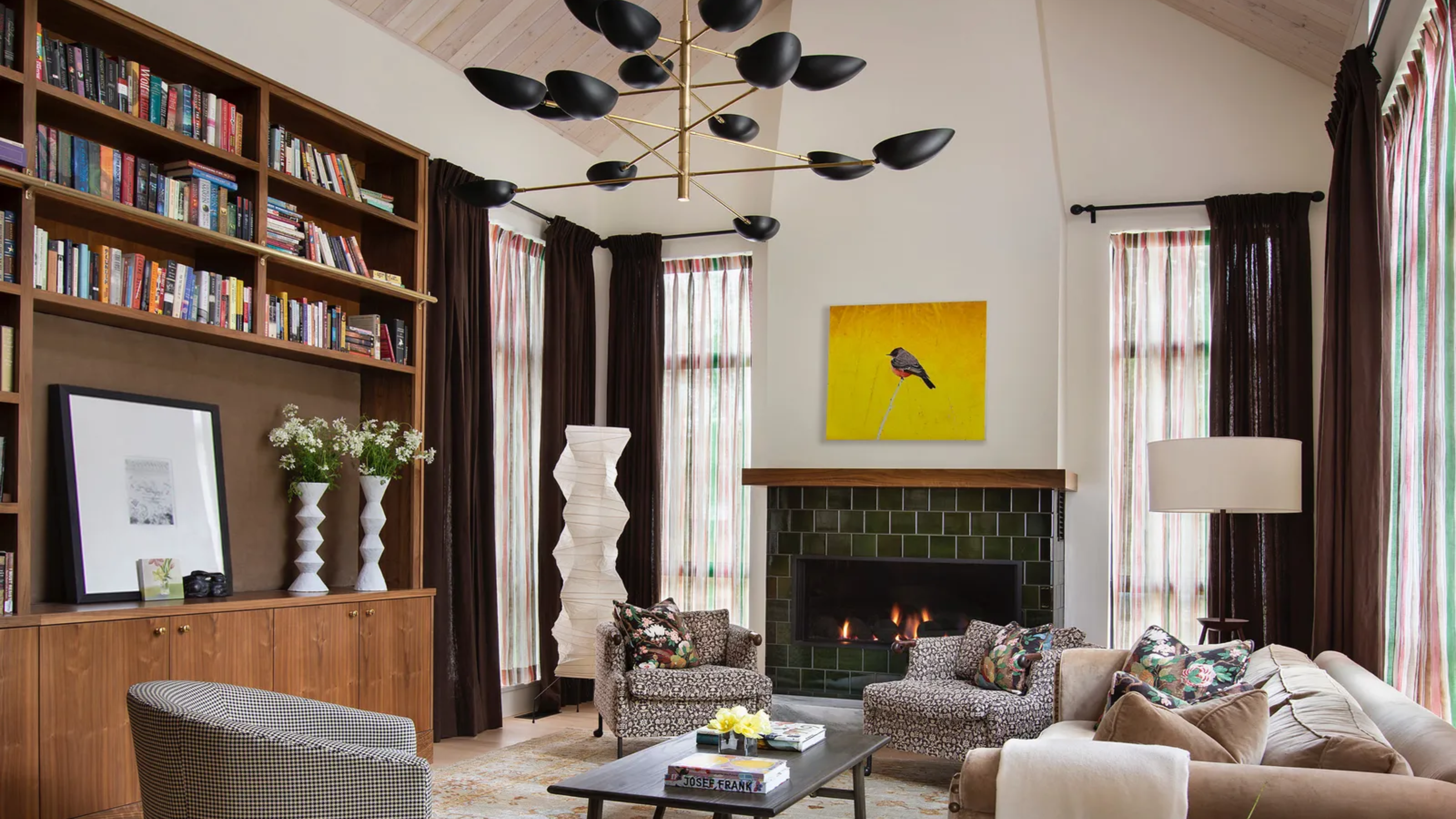 living room with a large black and gold chandelier, a built-in bookshelf wall, a couch, and three chairs