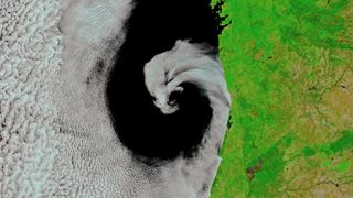 A spiral of cloud nestled along a coastline