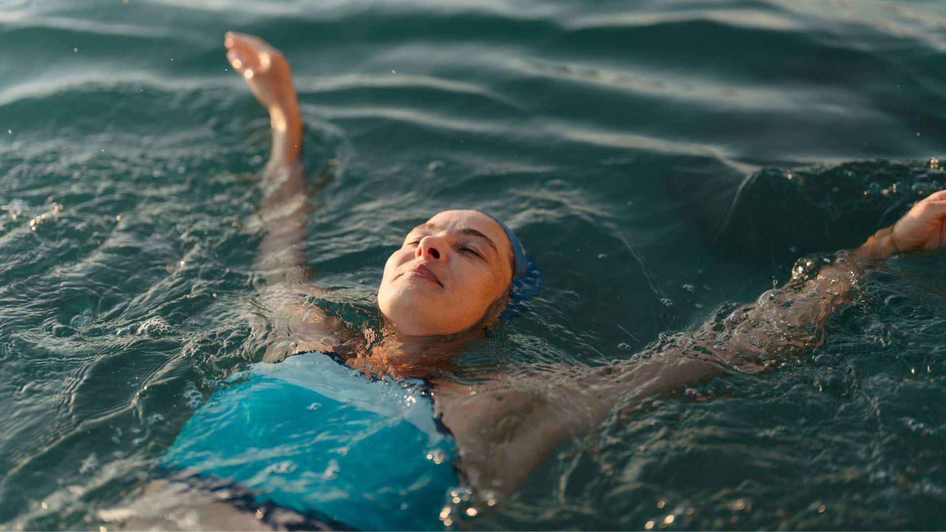 Woman on her back in outdoor pool, wearing swimming costume, representing how many calories does swimming burn