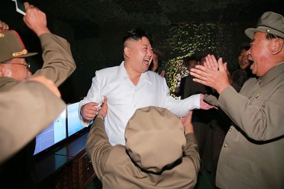 North Korean leader Kim Jong Un laughs with subordinates