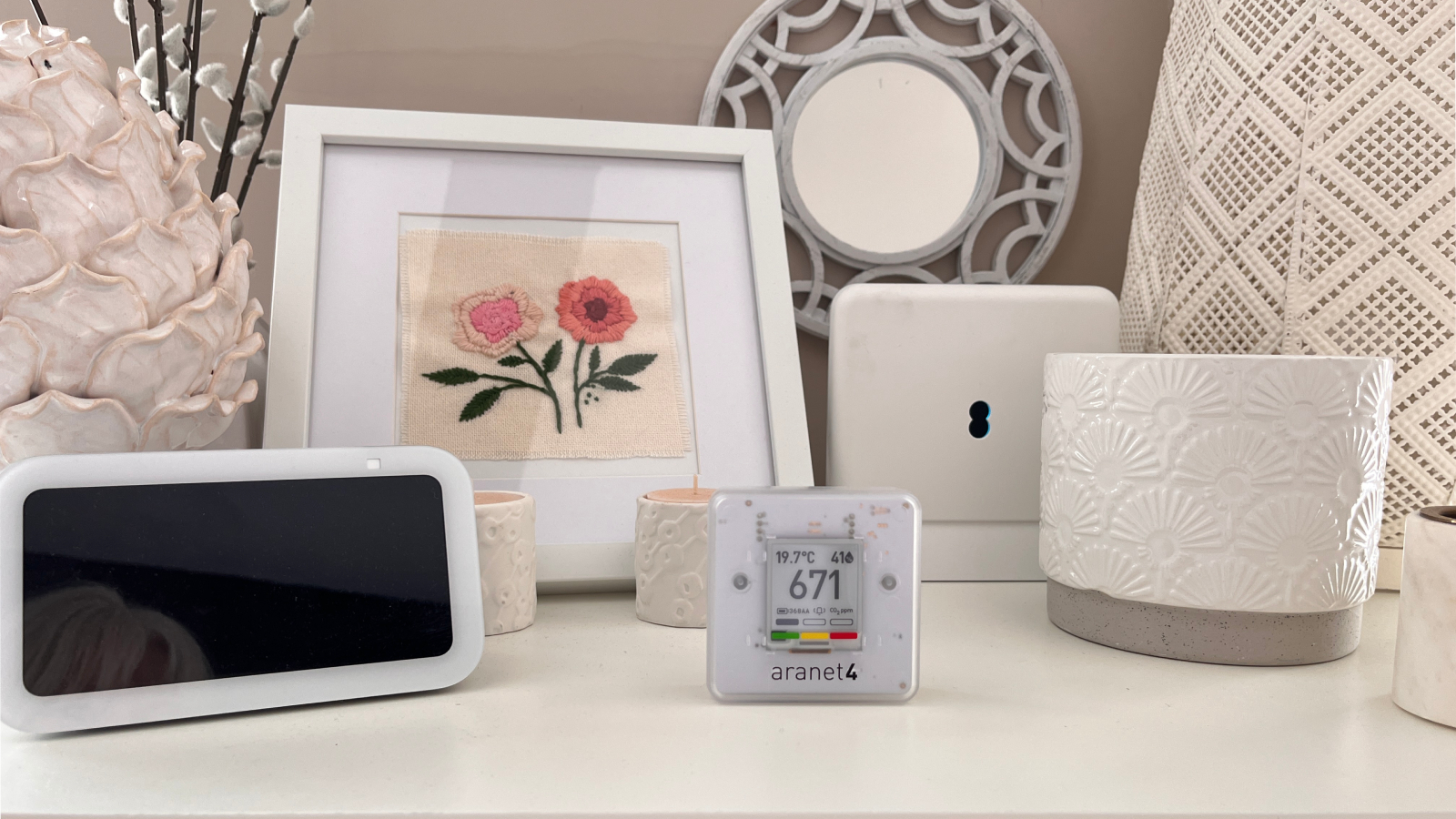 aranet4 home monitor on top of unit with decorative items and other display monitors