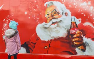 A little girl looking at the Christmas Coca Cola truck as it arrives in Bournemouth