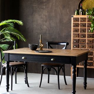 A moody dining room with a wooden cabinet and dining table in the centre