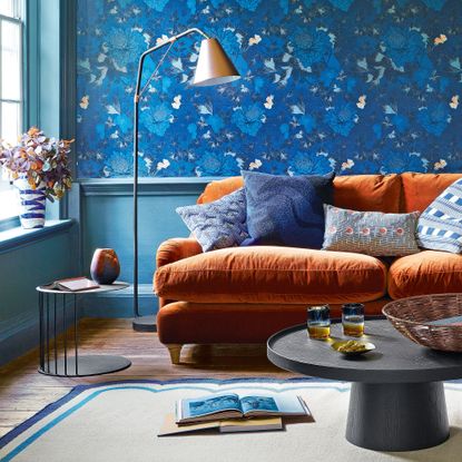 Blue living room with wallpapered wall and blue woodwork, plus orange velvet sofa