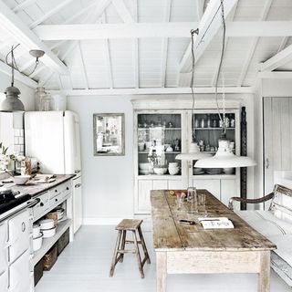 white kitchen with cupboard and wooden table