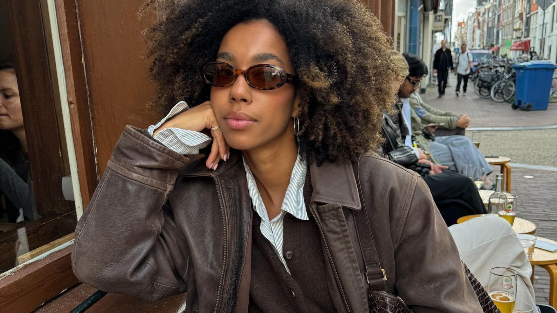 Influencer @amaka.hamelijnck wears a brown cardigan with a brown leather jacket and black boots.