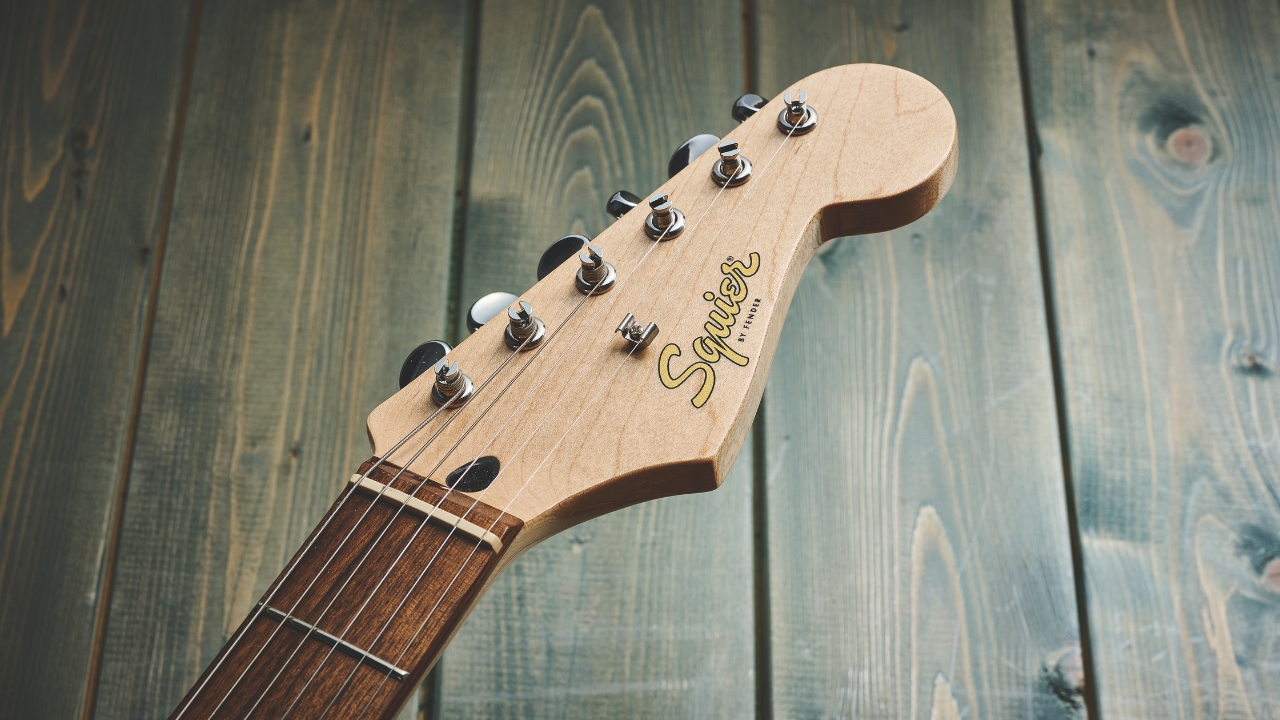 The headstock of a Squier electric guitar