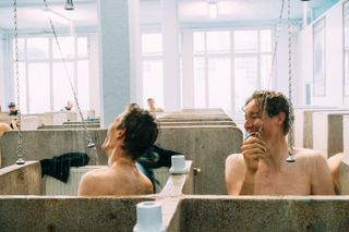 Riders laugh as they shower in the Roubaix velodrome showers after the race