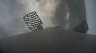 The first stage of a SpaceX Falcon 9 rocket topples onto its side after splashing down in the ocean during a failed landing attempt on Dec. 5, 2018. The horizon is vertical, at right; the waffle-iron-looking things are two of the booster's "grid fins." The Falcon 9 successfully completed its main mission that day, sending a robotic Dragon cargo capsule toward the International Space Station for NASA.