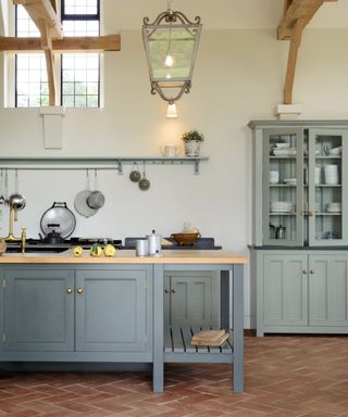 light blue modern farmhouse kitchen with terracotta floors and wooden ceiling beams