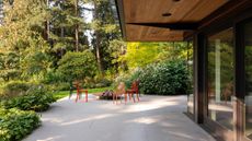 large patio with red chairs around a firepit and garden surrounding