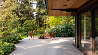 large patio with red chairs around a firepit and garden surrounding