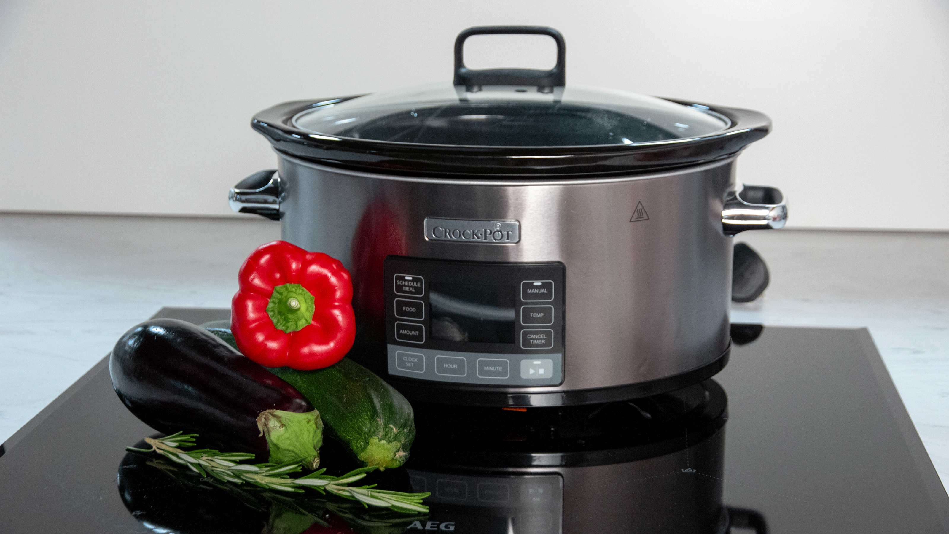 Silver slow cooker with vegetables on hob
