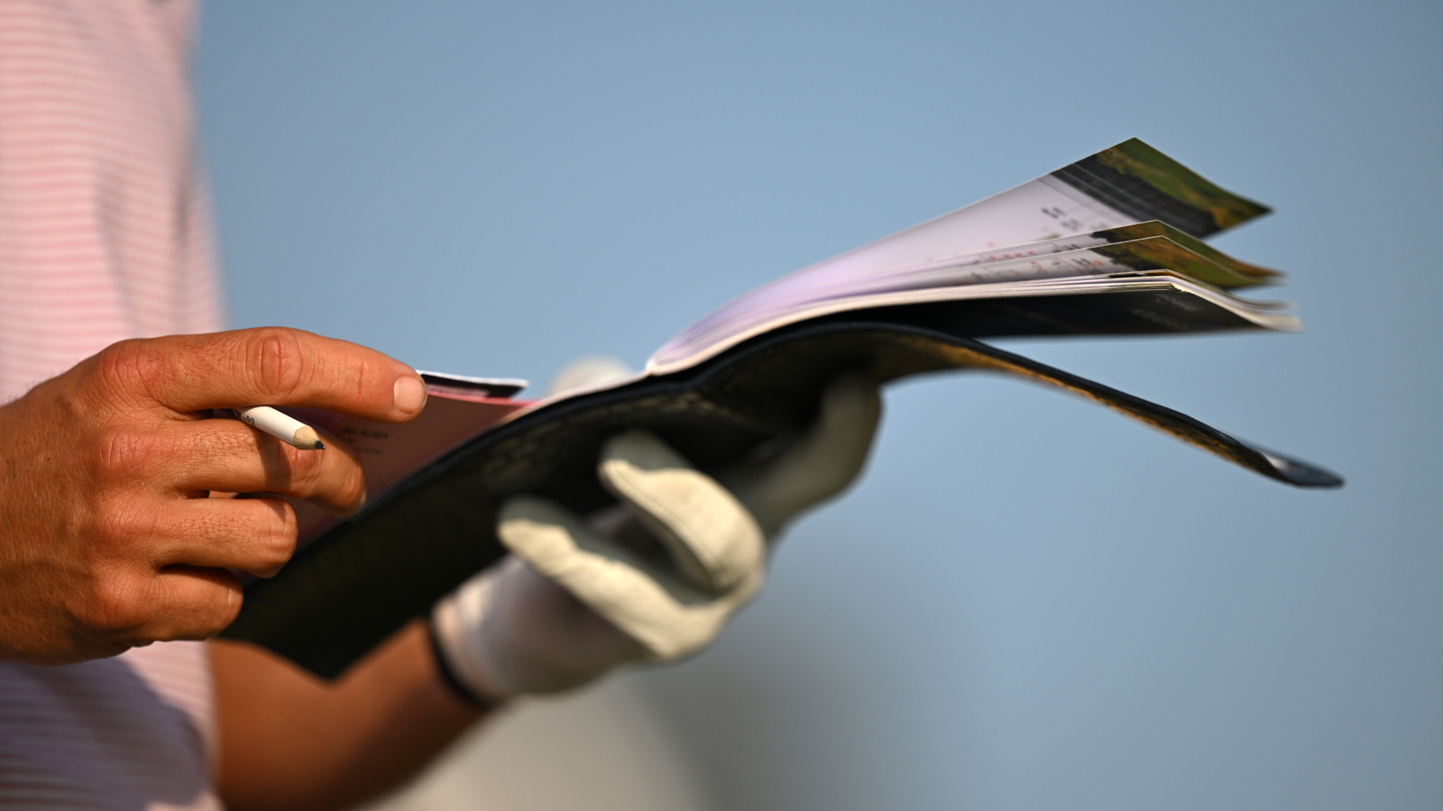 A golfer looks through a yardage book