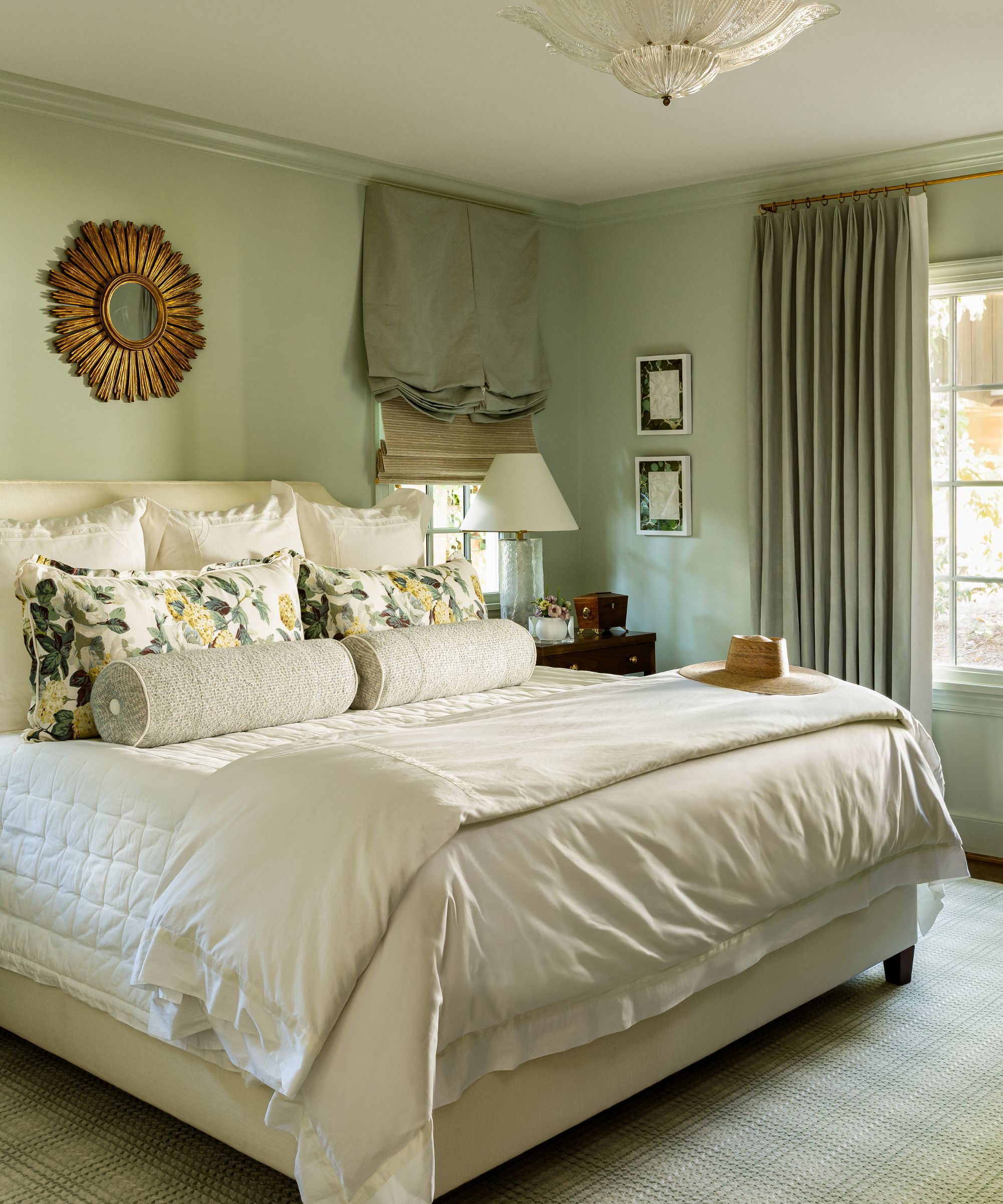 sage green bedroom walls and a large bed with warm white bedding and traditional decor
