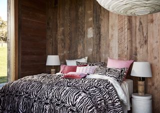 Bedroom interior with wood panelling paneling with zebra bedding cushions