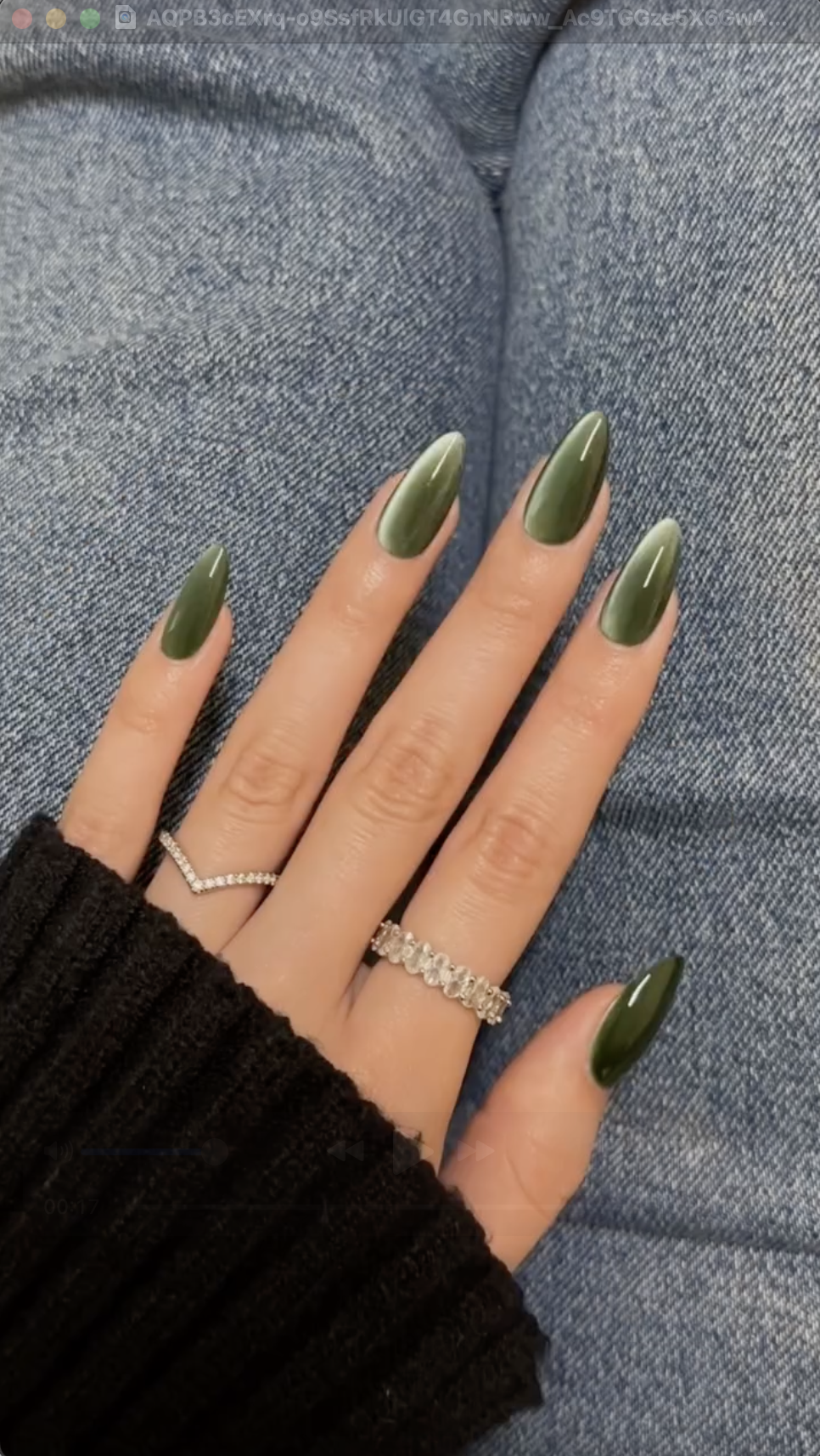 Close-up photo of a person&amp;rsquo;s hand showcasing a green velvet manicure on almond nails.