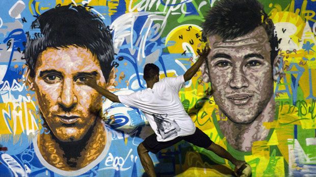 Youngsters play football in front of a World Cup mural in a Rio favela