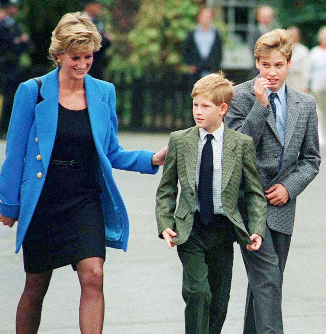 Princess Diana, Prince Harry and Prince William walking outside at Eton College in suits