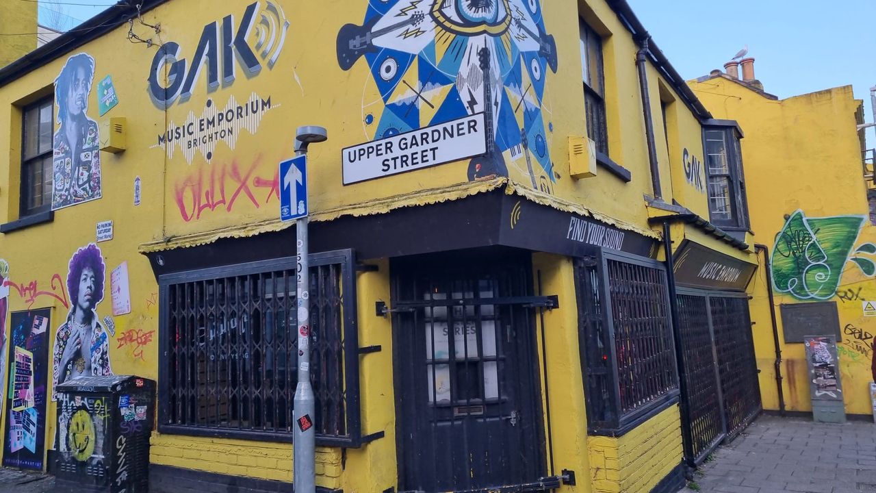 GAK Music Emporium bright yellow shop front in Brighton, with graffiti of various artists, including Jimi Hendrix