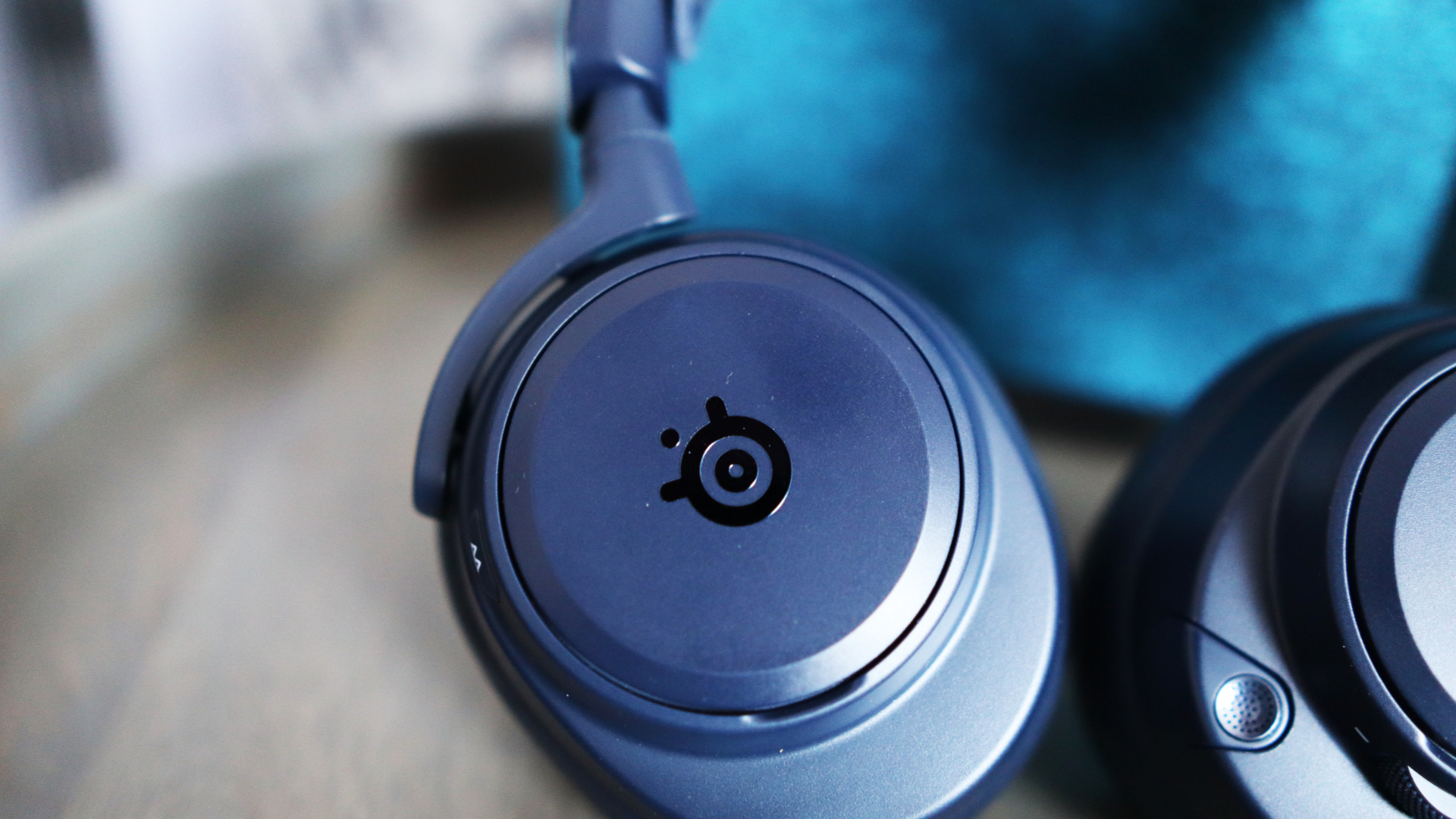 The Arctis Nova Pro Omni from SteelSeries on a desk and chair with accessories.