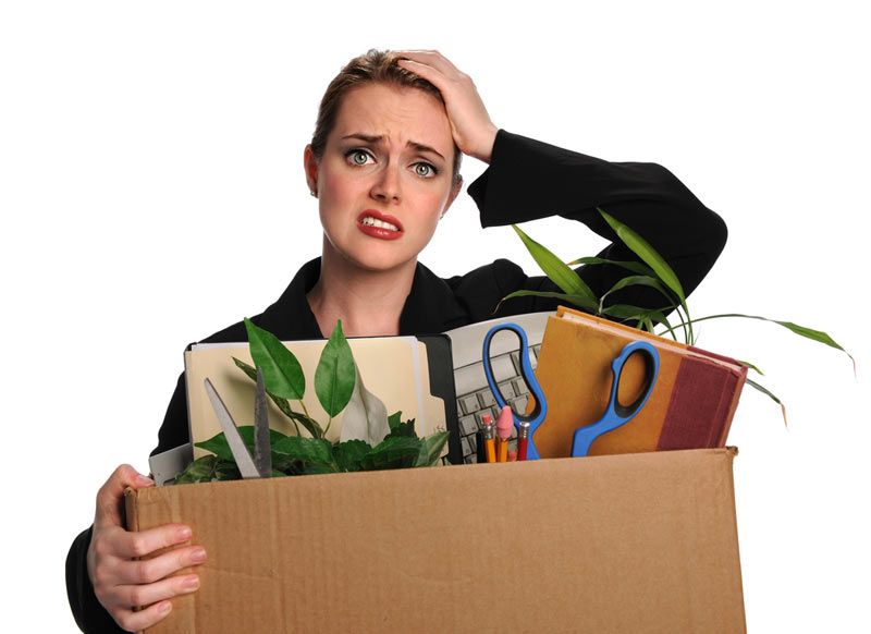 upset businesswoman carrying a box of supplies after losing a job