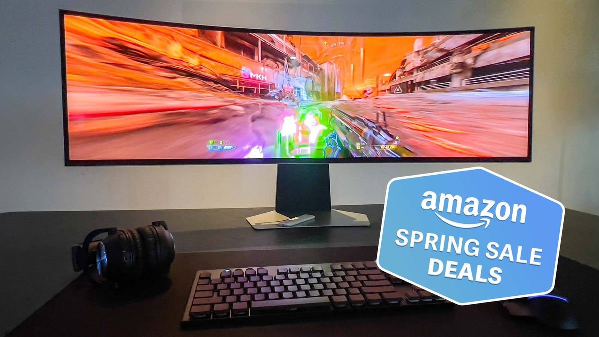 Samsung Odyssey OLED G9 on table with keyboard and headphones with Tom&#039;s Guide Amazon Spring Sale Deals badge