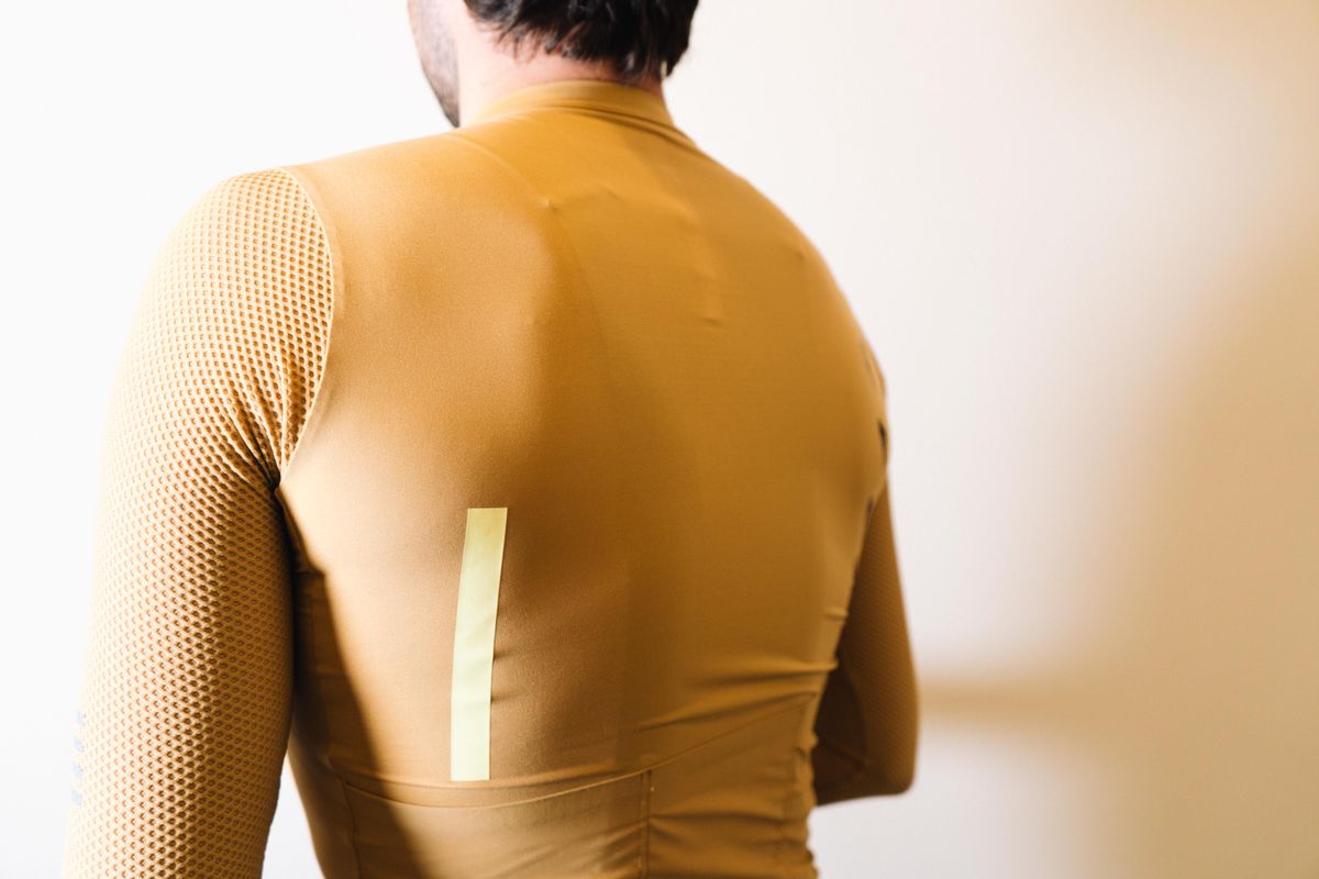 A white man in a tan jersey against a white wall