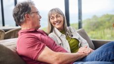 Smiling mature woman talking with her husband on their living room sofa
