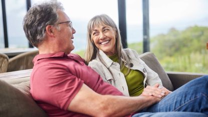 Smiling mature woman talking with her husband on their living room sofa