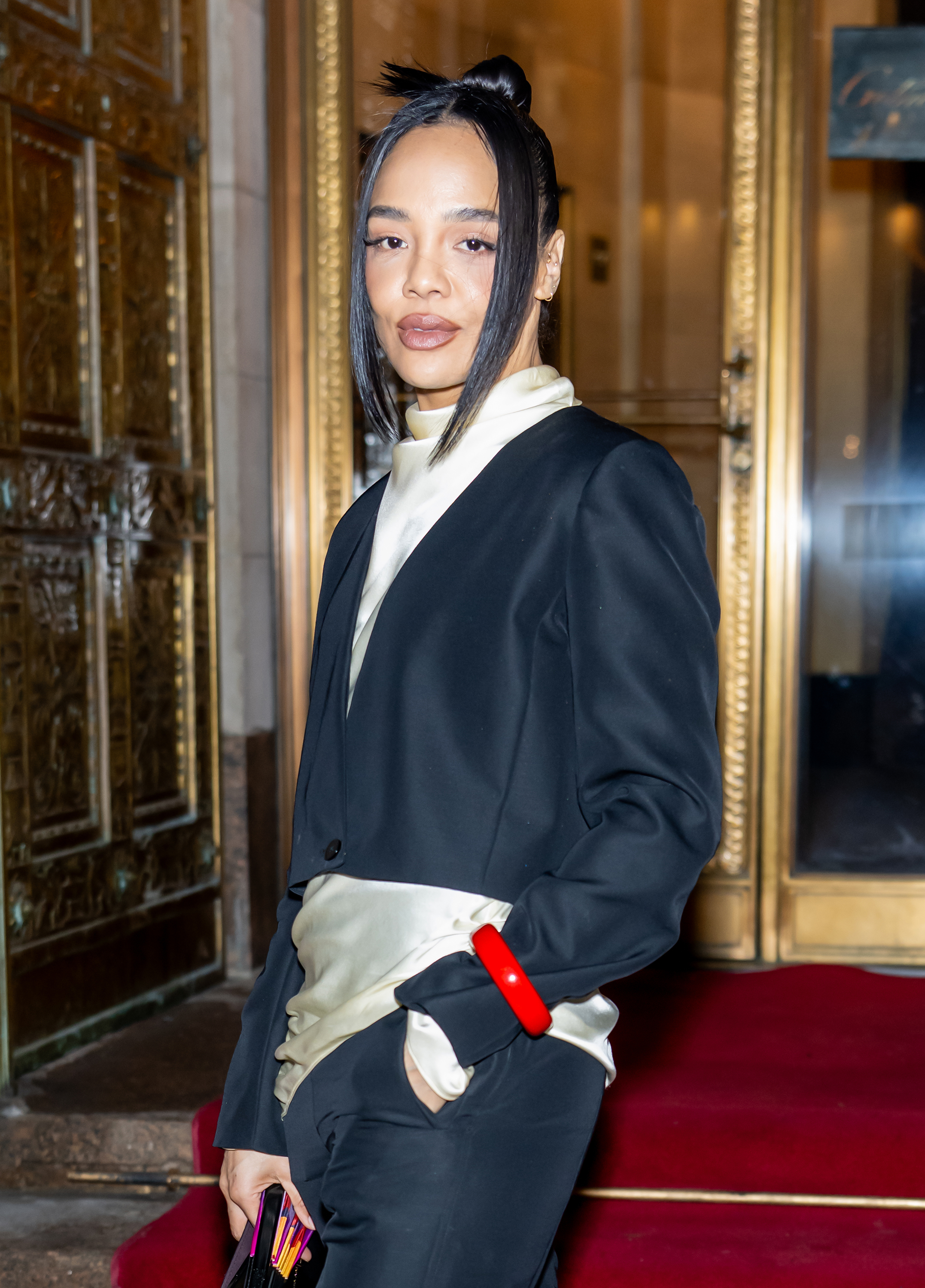 a black woman with dark hair posing for paparazzi in front of a hotel