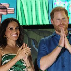 Meghan Markle wears a green and white leaf-print dress, and applauds next to husband Prince Harry