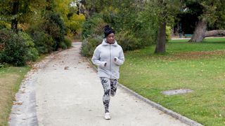 Woman running through a park in the morning