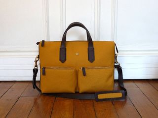 Caramel-coloured leather bag with dark leather handles and two front zip-up pockets