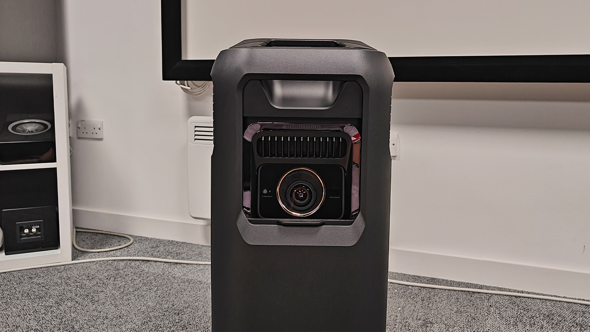 Soundcore Nebula X1 Pro home cinema projector on grey carpet in test room showing lens