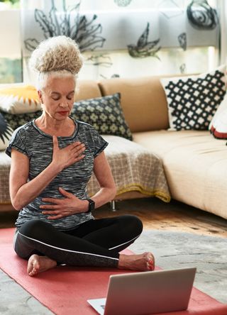 Woman doing a yoga pose with a laptop