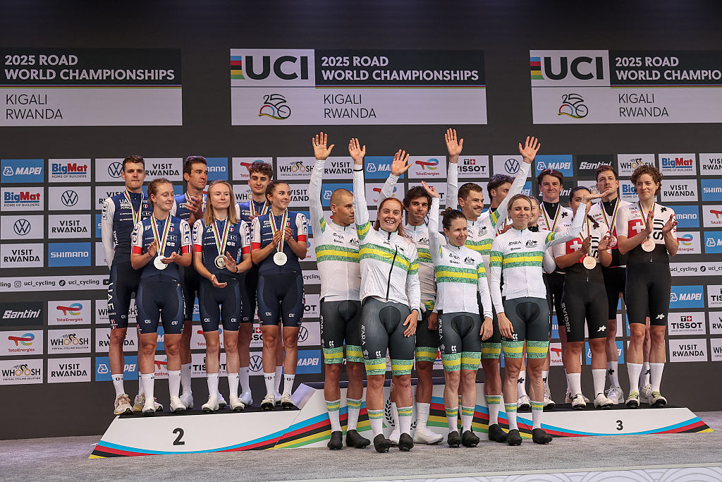 Silver medallists French team riders (L), gold medallists Australian team riders (C) and bronze medallists Swiss team riders (R) celebrate on the podium following the team time trial mixed relay cycling event during the UCI 2025 Road World Championships, in Kigali, on September 24, 2025. (Photo by Anne-Christine POUJOULAT / AFP)