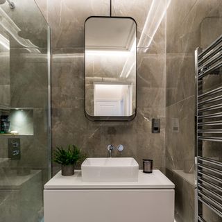 Natural toned marble wall in bathroom with sink and mirror