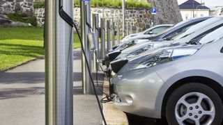 A row of electric cars charging at a charging station