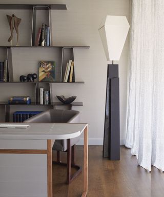 Grey desk with curved wooden legs, black lamp