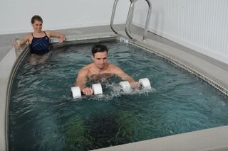 Best swim spas: A man performs weights exercises in an indoor SwimEx swim spa
