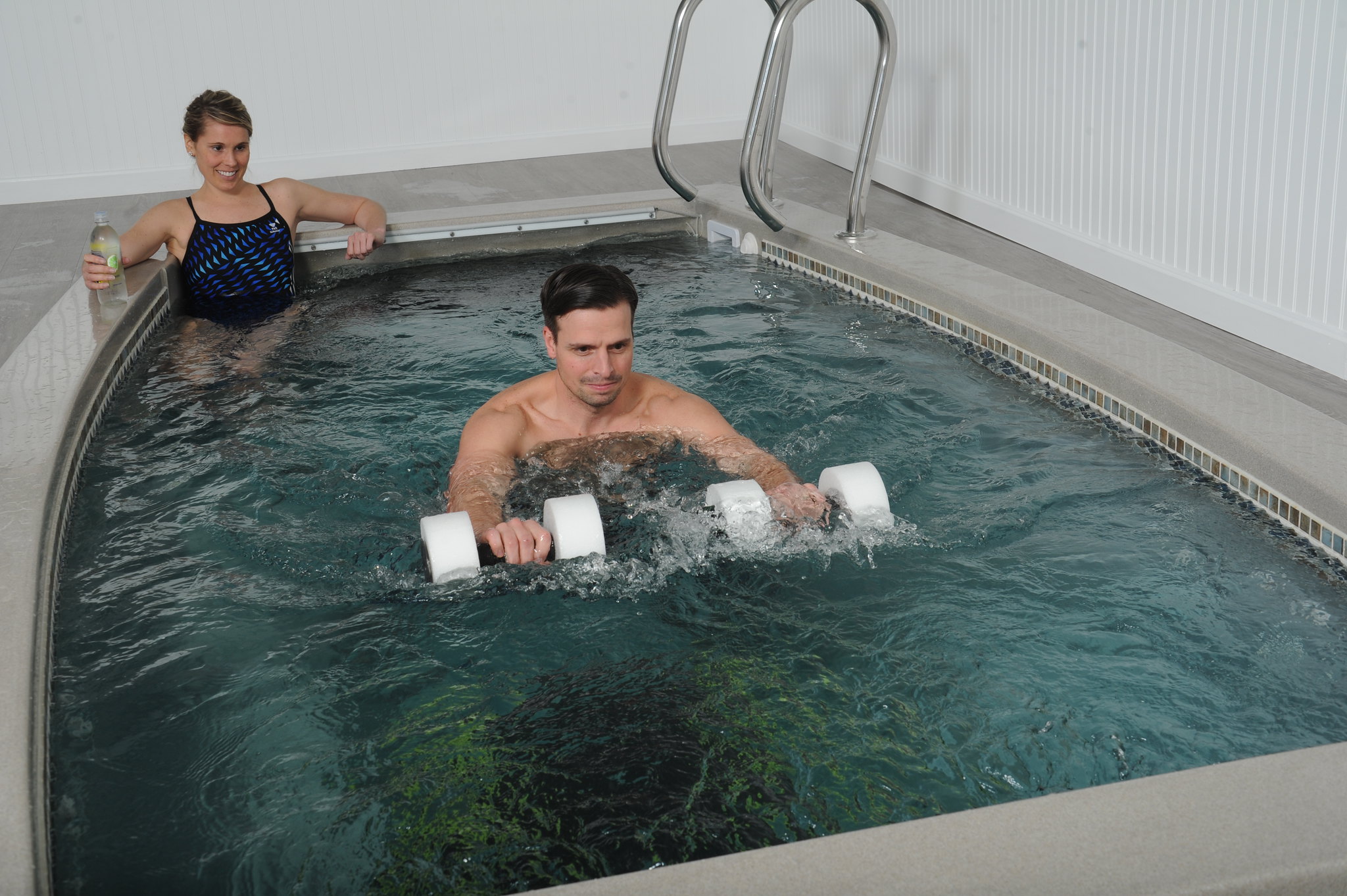 Best swim spas: A man performs weights exercises in an indoor SwimEx swim spa