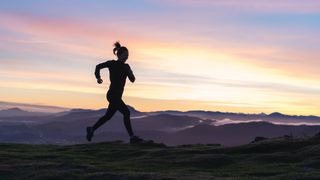 Woman running on hill at sunrise